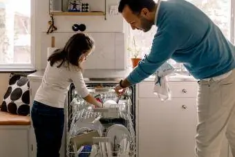 Isä ja tytär järjestämässä astioita astianpesukoneessa keittiössä