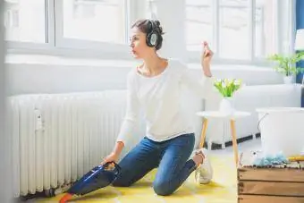 Žena kod kuće sa slušalicama lebde po podu