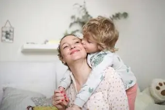 En liten gutt som tar moren sin i armene på soverommet