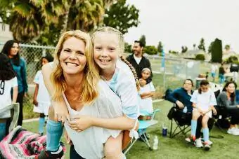 Naeratav ema teeb pärast jalgpallimängu tütrele notsu seljas