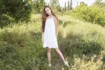 Chica de pie en el campo de hierba vistiendo un vestido blanco de verano