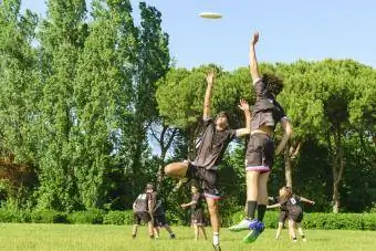 Os adolescentes da equipe usam jogando um jogo de frisbee no parque