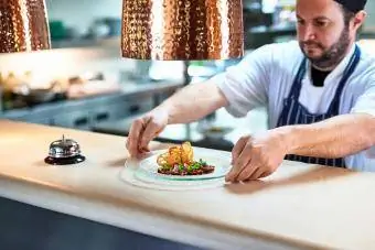 Šéfkuchár umiestňuje tanier s jedlom na obslužný pult