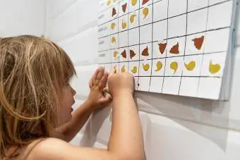 niña mirando y señalando su calendario de pipí y caca