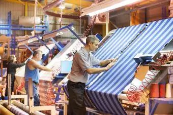 Tekstil işçileri fabrikada çizgili dokuma ipliğini inceliyor