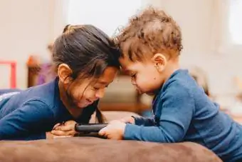 طفل رضيع يستخدم الهاتف الذكي مع أخته على الأريكة