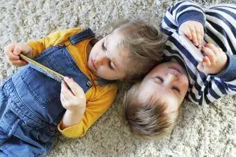 Hermano y hermana acostados mirando teléfonos