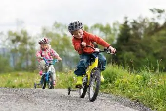 Băiețelul și sora lui mai mică merg cu bicicleta în aer liber