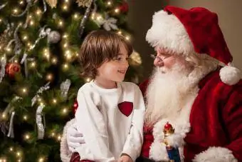 Berniukas, sėdintis ant Kalėdų Senelio kelių, kalbasi