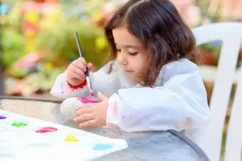 småbarn flicka måla en sten