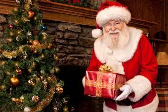 santa claus oleh pokok Krismas dengan hadiah