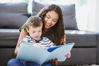 Opiekunka do dziecka i dziecko spędzają czas razem czytając książkę w salonie