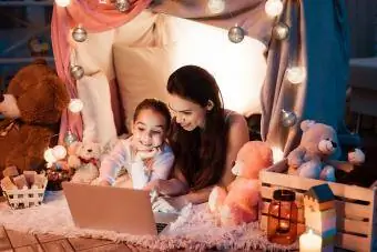 Mor och dotter tittar på film på laptop i kuddhus