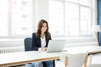 Geschäftsfrau sitzt am Schreibtisch im Büro und arbeitet am Laptop