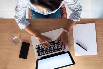 سيدة أعمال شابة أنيقة تعمل مع جهاز الكمبيوتر المحمول الخاص بها في المكتب. منظر علوي.
