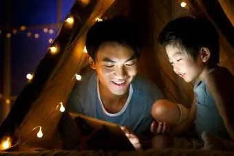 Vader en zoon in een tent die tablet samen gebruiken