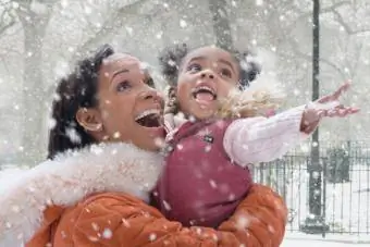 Mama drži hčerko v padajočem snegu