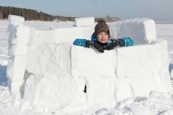 Menino construindo forte de neve