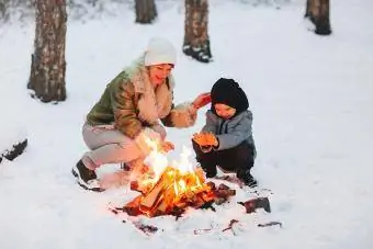 Madre e hijo en la nieve durante el invierno con hoguera