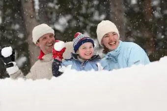 Baba, anne ve oğul kar topu atıyor