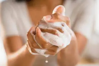 Persona che insapona le mani con sapone