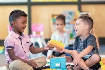 Alunos da pré-escola felizes brincando juntos e compartilhando em sala de aula