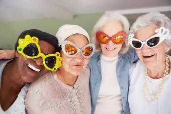 Een groep oudere vrouwen die een funky zonnebril dragen terwijl ze in een verpleeghuis staan
