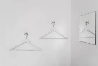 Kleiderbügel hängen an Haken an der weißen Wand