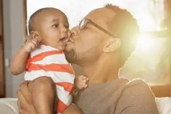 Tėvas bučiuoja sūnų į skruostą