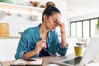 vrouw zit achter de computer en voelt de stress van haar werk