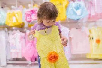 Schattig glimlachend klein meisje in de kledingwinkel
