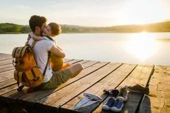 Un joven y su hijo pasan un buen rato juntos mientras están sentados en el muelle de un lago