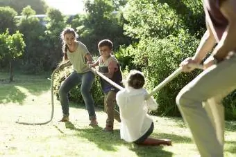 Ģimene parkā spēlē virves vilkšanu