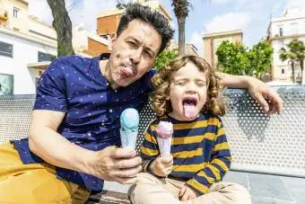 Sretni otac i sin sjede na klupi i uživaju u sladoledu