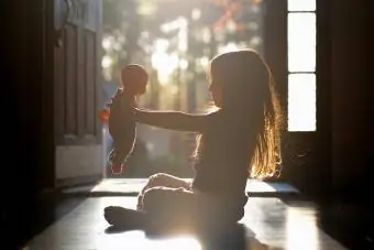 Niña sentada en un pasillo sosteniendo su muñeca