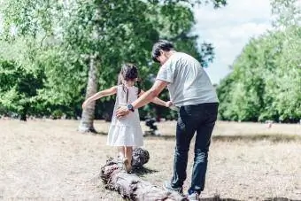 Şefkatli bekar baba, kızının bir ağaç gövdesi boyunca yürümesine yardım ediyor