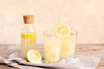 Pote de saborosa limonada fresca com limões no fundo