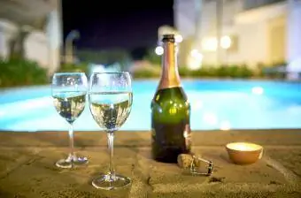 Dois copos de prosecco à beira da piscina à noite