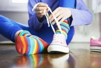 Бага насны хүүхэд өнгө өнгийн оймсоор гутлын үдээс уяж байна