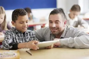 लड़का टैबलेट कंप्यूटर पर शिक्षक का स्कूलवर्क दिखा रहा है