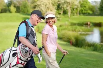 Munter modent par går på en golfbane