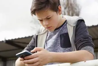 Hämmentynyt teinipoika katselee älypuhelinta