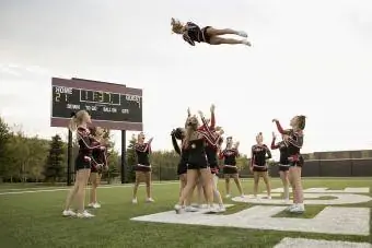 High School cheerleading-lag som øver på fotballbanen