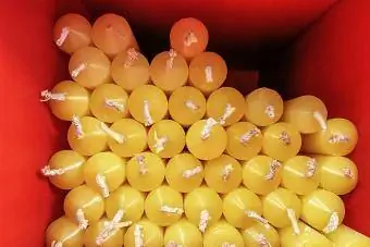 Grup d'espelmes grogues amb metxes blanques col·locades en una caixa quadrada vermella