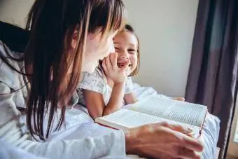 Mama ir dukra skaito knygą lovoje