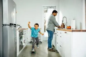 Dječak vozi skejt u blizini oca u kuhinji