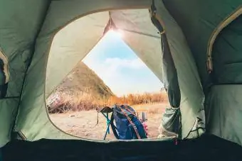 İlkbahar ve yaz sezonunda dağın tepesinde kamp çadırı ve sırt çantasıyla doğada yolculuk tutkusu ve rahatlayın