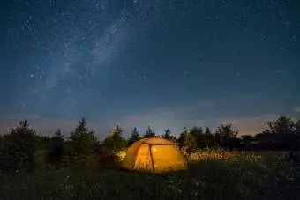 Tienda de campaña iluminada bajo el cielo estrellado.