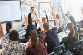 alunos levantando as mãos na sala de aula