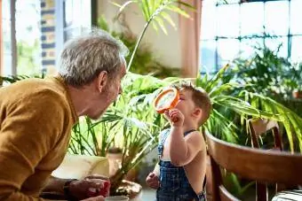 Barnebarn studerer bestefars ansikt gjennom forstørrelsesglass